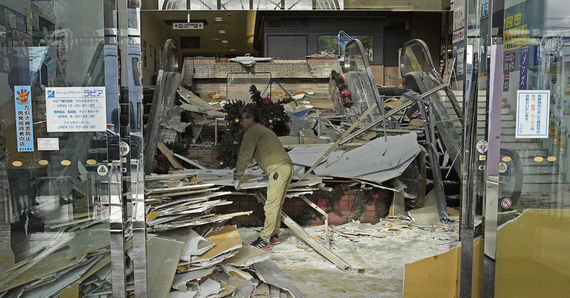 A worker clears debris inside a damaged shopping center after Japan's 7.5 earthquake