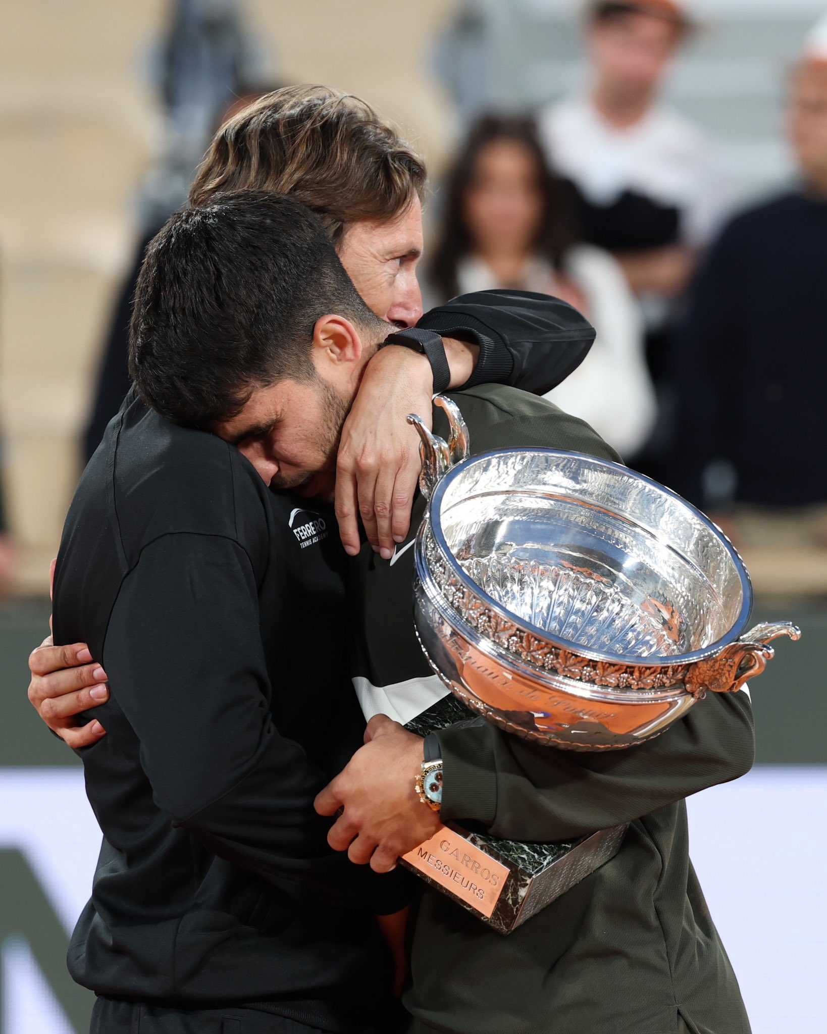 Carlos Alcaraz embraces coach Juan Carlos Ferrero while holding a trophy