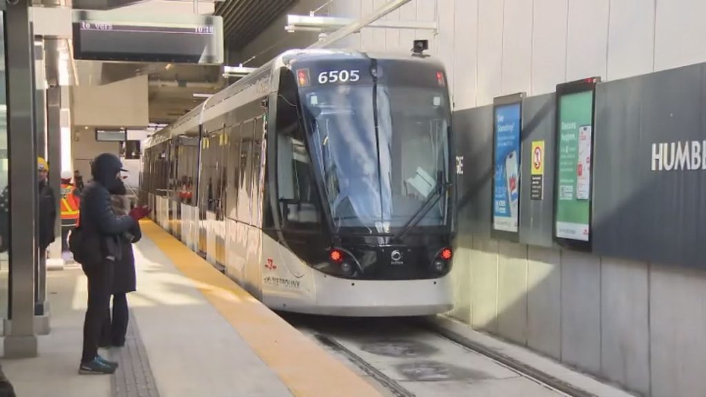 Finch West LRT train at street level in northwest Toronto with passengers waiting on the platform
