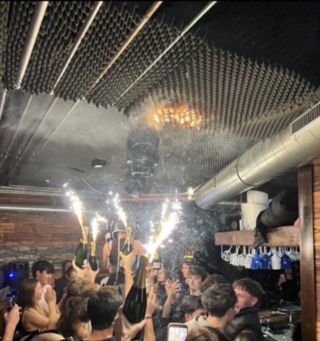 Sparklers raised in a crowded bar as flames appear on the ceiling in Crans-Montana, Switzerland