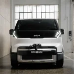 Kia PV5 Cargo electric van in white parked inside an industrial warehouse during an official Australian launch preview, showing the front design, LED lighting, and commercial EV styling.