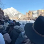 Crowds gather along Banff Avenue during the Banff skijor event with snow-covered mountains in the background before the 2027 event cancellation.
