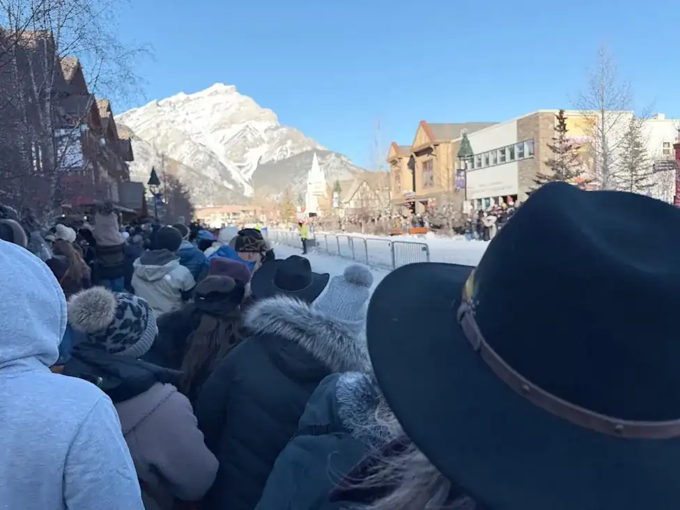 Crowds gather along Banff Avenue during the Banff skijor event with snow-covered mountains in the background before the 2027 event cancellation.