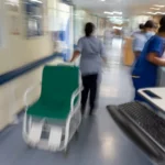 England hospital corridor during heatwave as NHS staff respond to rising patient demand amid equipment and cooling system disruptions