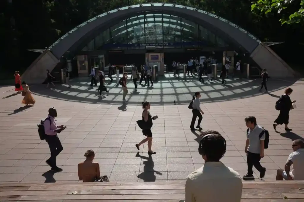 Commuters walk outside Canary Wharf Station in London during an extreme heatwave as major rail services face cancellations, delays and reduced timetables due to high temperatures.