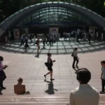 Commuters walk outside Canary Wharf Station in London during an extreme heatwave as major rail services face cancellations, delays and reduced timetables due to high temperatures.