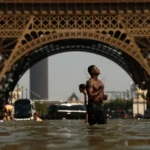 People cool off in the Trocadéro Fountain beneath the Eiffel Tower during an intense heatwave in Paris, France, as extreme temperatures prompt the postponement of the Paris Pride March.