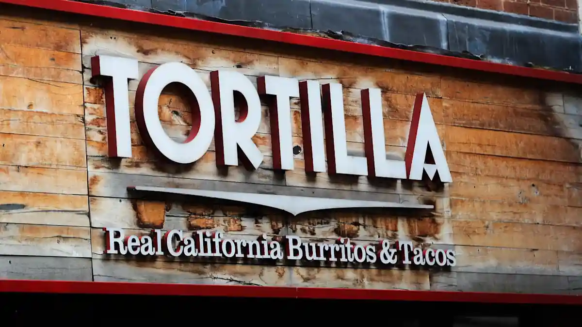 Tortilla Mexican Grill storefront sign displayed on a wooden exterior facade with the slogan "Real California Burritos & Tacos," representing the restaurant chain amid news of its AIM share suspension following a £2.5 million accounting error