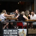 Customers dining on a busy Canadian restaurant patio during summer.