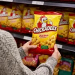 Shopper holding a recalled Chickadees snack packet in an Australian supermarket following the Food Recall Australia warning over possible rubber contamination