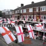 St George’s Cross flags displayed across homes on a residential street in England.