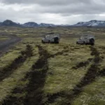 Two off-road vehicles leaving tyre tracks across fragile terrain in Iceland’s Highlands