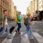 Group of travelers walking with suitcases across a European city street, representing Groupia holiday bookings affected after the travel company entered administration.