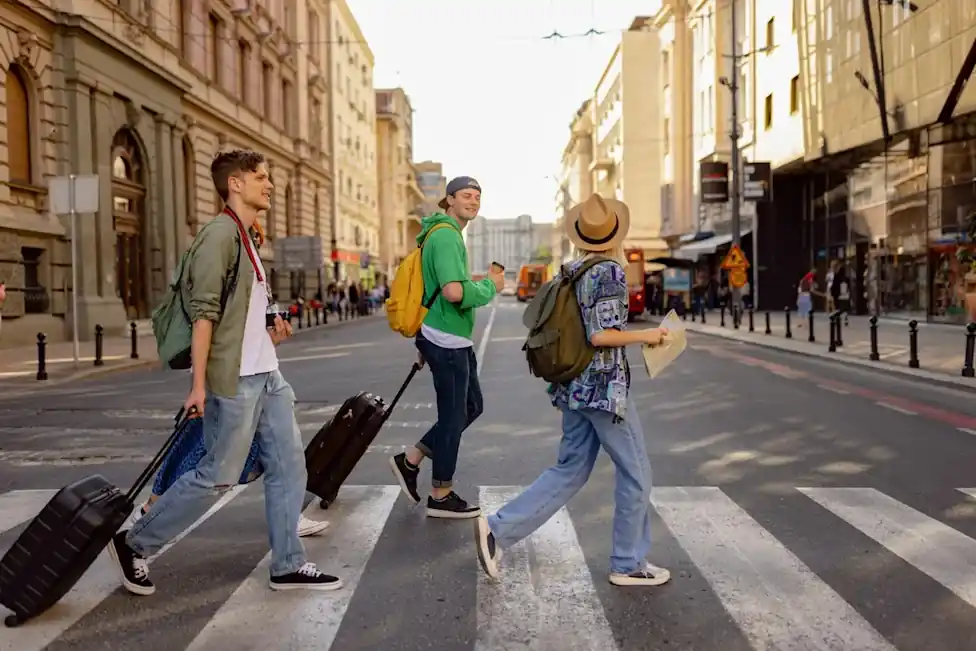 Group of travelers walking with suitcases across a European city street, representing Groupia holiday bookings affected after the travel company entered administration.