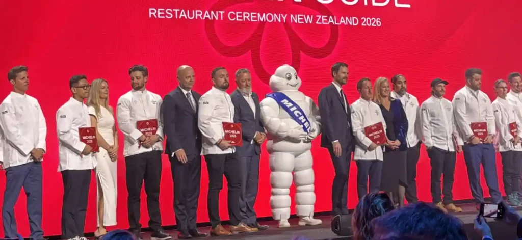 "Chefs and hospitality leaders stand on stage during the Michelin Guide New Zealand 2026 awards ceremony in Auckland, celebrating the country's first Michelin-starred restaurants."
