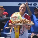 Joey Chestnut celebrates after winning the Nathan's Famous Hot Dog Eating Contest at Coney Island while holding the championship Mustard Belt and a tray of hot dogs during the Fourth of July competition