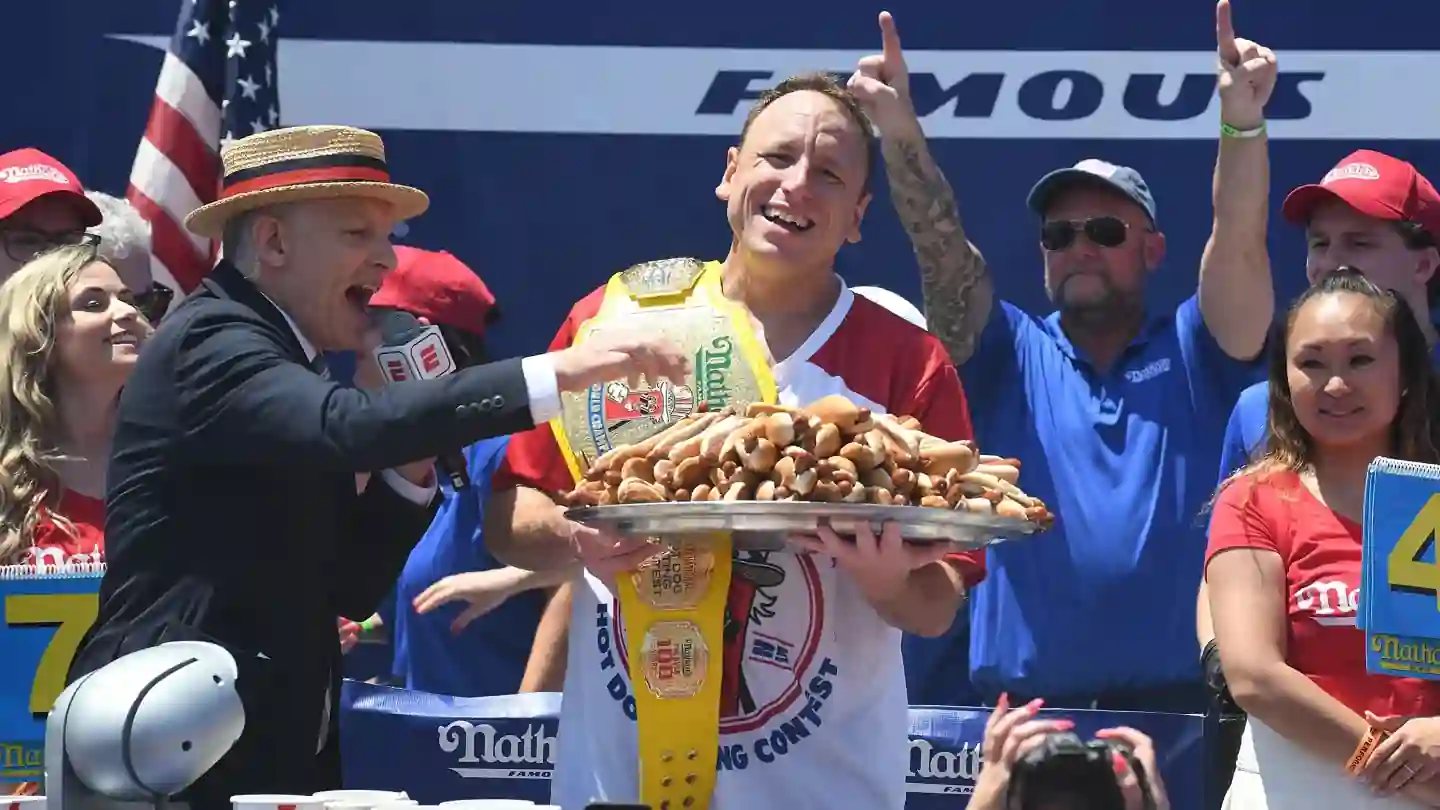 Joey Chestnut celebrates after winning the Nathan's Famous Hot Dog Eating Contest at Coney Island while holding the championship Mustard Belt and a tray of hot dogs during the Fourth of July competition