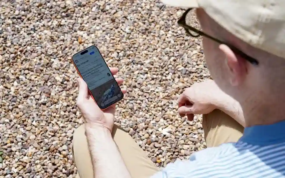 Person using a smartphone outdoors during a heatwave to illustrate tips for preventing phone overheating in hot weather.