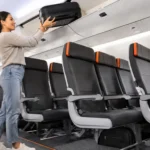 Jetstar passenger placing a carry-on suitcase in an overhead locker before new baggage rules begin in 2027