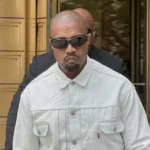 Kanye West pictured wearing sunglasses and a white jacket.