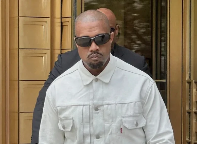 Kanye West pictured wearing sunglasses and a white jacket.