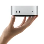 Apple Mac mini compact desktop held in hand against a white background