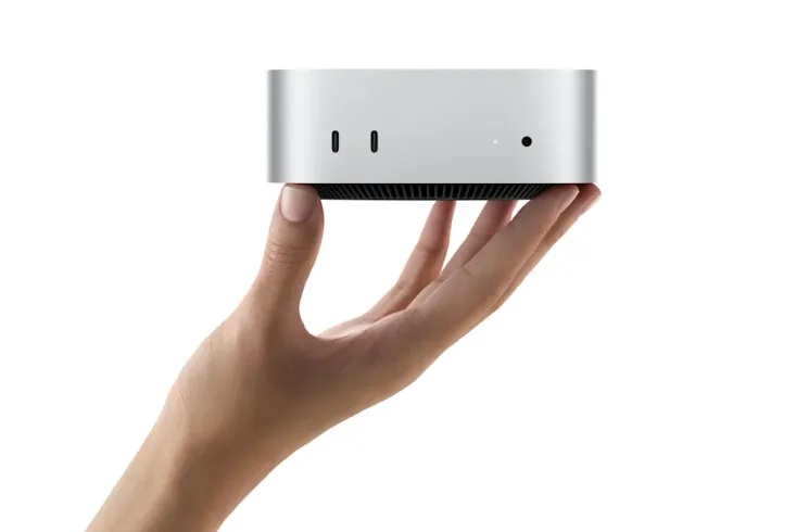 Apple Mac mini compact desktop held in hand against a white background