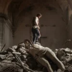 The Odyssey scene featuring a warrior standing over a fallen statue amid ancient ruins