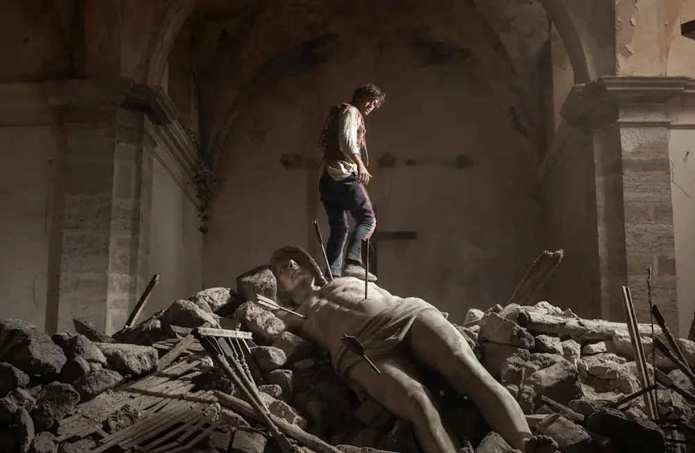 The Odyssey scene featuring a warrior standing over a fallen statue amid ancient ruins